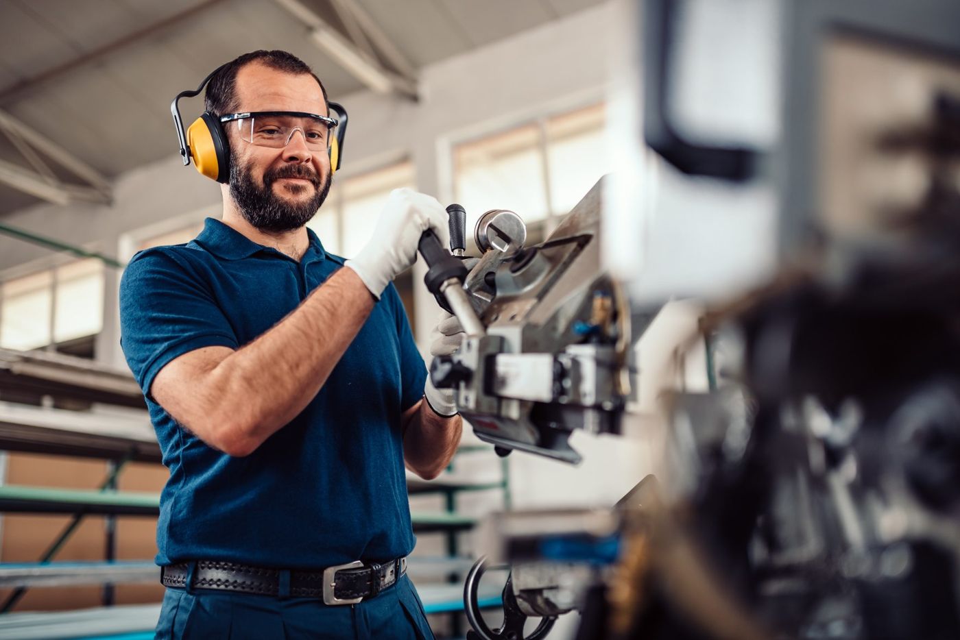Machinist in safety glasses and hearing protection operating equipment