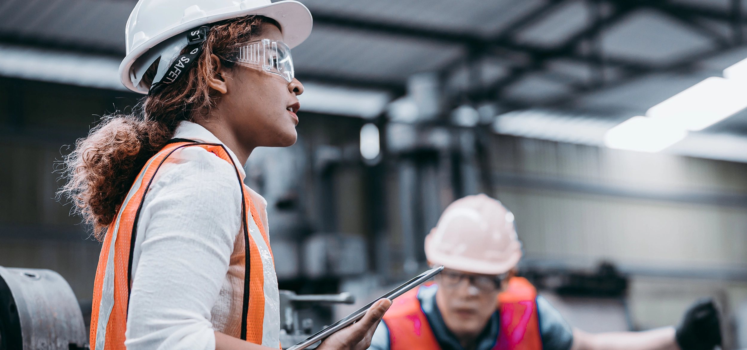 Safety lead with a tablet speaking with a colleague on a plant floor